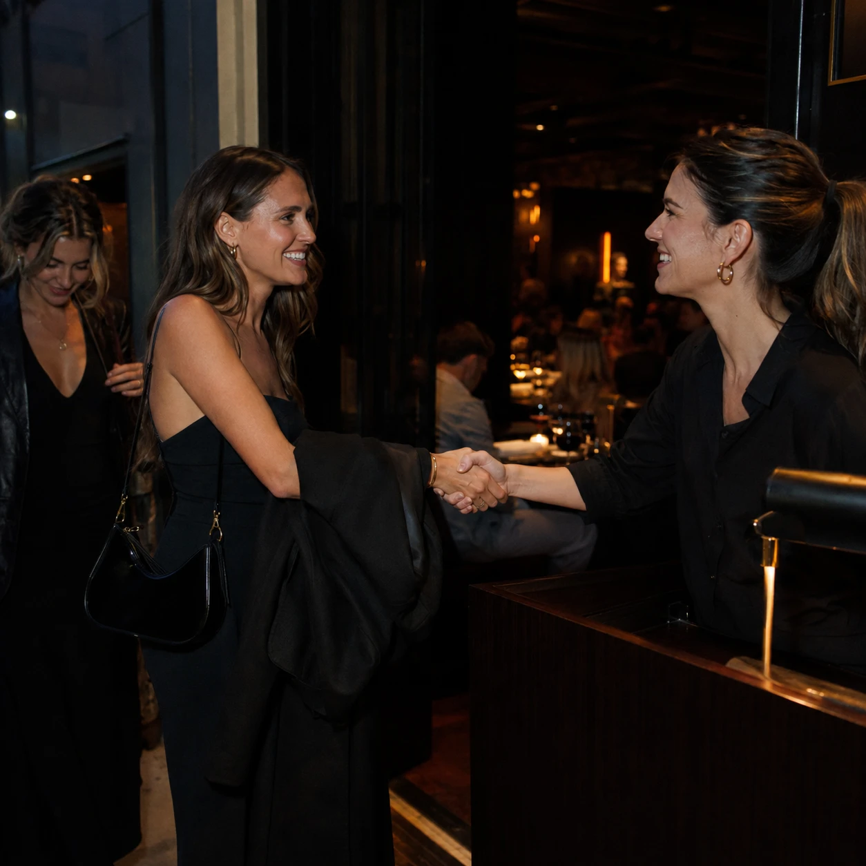 A host shaking hands with an arriving guest across the host stand